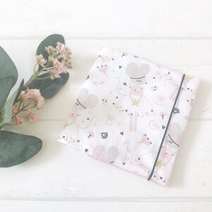 Könnte beinhalten: Ein weißes Stoffquadrat mit einem rosa und grauen Druck von Mäusen, die Tüllröcke tragen und Zauberstäbe halten. Der Stoff hat einen schwarzen Saum an den Rändern.
