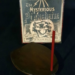 Puede incluir: Planchette de madera vintage con un puntero rojo, en una caja con el texto "The Mysterious Planchette Complete with Ouija-Phone or Talking Board".