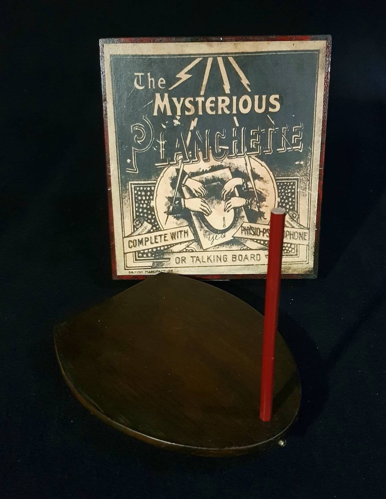 Puede incluir: Planchette de madera vintage con un puntero rojo, en una caja con el texto "The Mysterious Planchette Complete with Ouija-Phone or Talking Board".