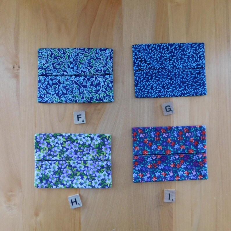 May include: Four rectangular fabric pouches with distinct patterns: top left features blue and green leaves, top right has a dark blue rice grain print, bottom left displays light purple flowers, and bottom right shows a dense floral pattern in red and blue.