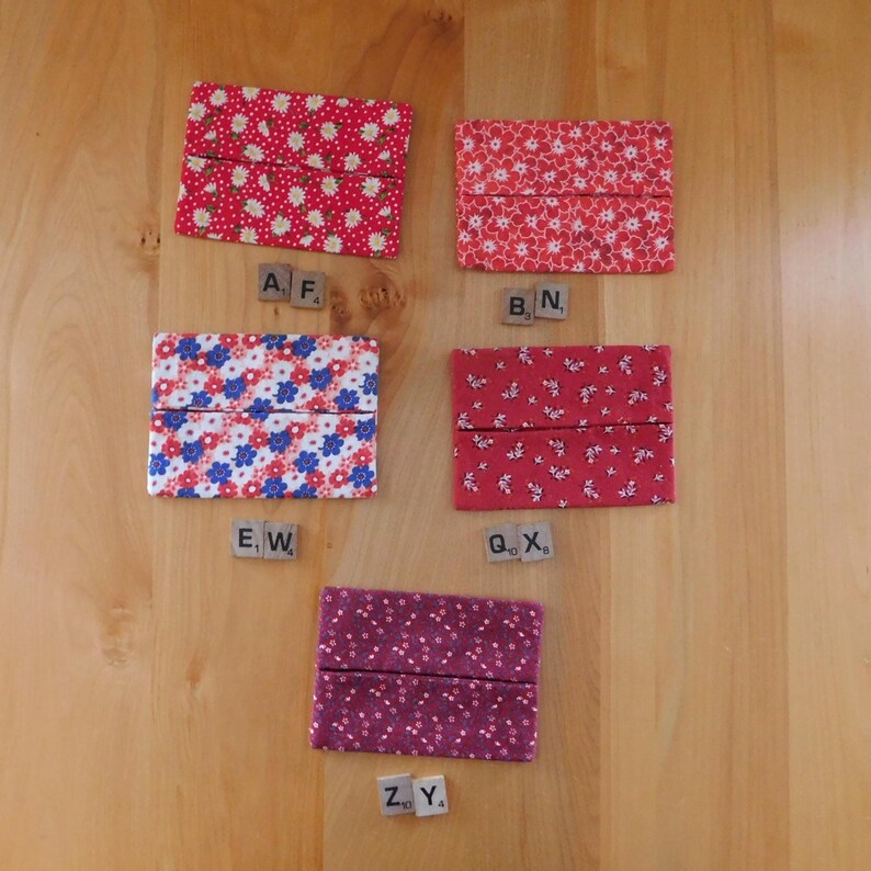 May include: Five rectangular fabric tissue holders featuring various floral patterns in shades of red, white, blue, and purple. Each holder is paired with small wooden letter tiles labelled AF, BN, EW, QX, and ZY, arranged in a vertical layout.