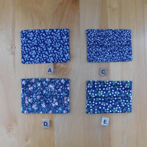 May include: Four rectangular fabric tissue holders featuring floral patterns in shades of blue, pink, and white. Each holder is labelled with a small wooden square tile marked with the letters A, C, D, or E, indicating distinct fabric designs.