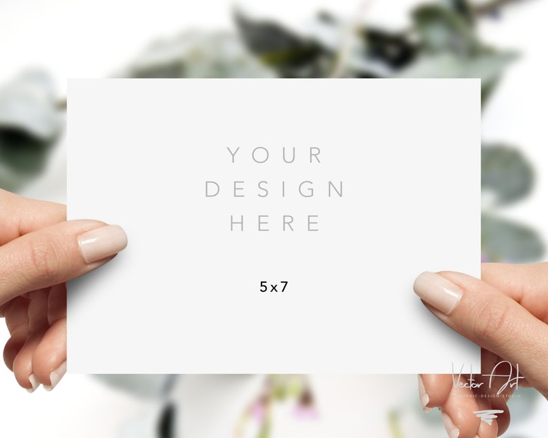 Puede incluir: Una tarjeta blanca de 5 x 7 pulgadas (12,7 x 17,8 cm) sostenida por dos manos. La tarjeta tiene el texto "YOUR DESIGN HERE" en una fuente gris claro. El fondo est&aacute; borroso con follaje verde.