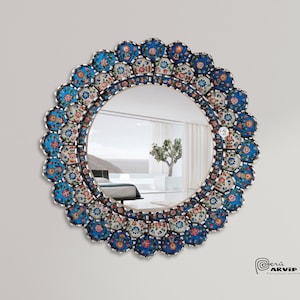 May include: A round mirror with a decorative frame made of blue, white and pink mosaic tiles. The frame features a floral pattern.