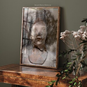 May include: A framed photograph of a woman with a distressed, ghostly appearance. The photo is in a simple, wooden frame and is displayed on a wooden table.