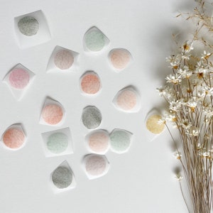 May include: Assortment of colorful watercolor circles on white paper. The circles are in various shades of pink, green, brown, and gray. The circles are arranged in a random pattern on the paper.