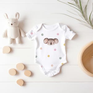 May include: White baby onesie with a watercolor koala face and pastel pink, green, and yellow polka dots.