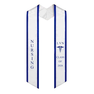 May include: A white graduation sash with blue edging and text. The sash displays "NURSING" on one side and "LVN CLASS OF 2026" with a caduceus symbol on the other. The sash is made of a shiny, satin-like material.