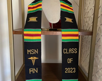Könnte beinhalten: Schwarzer Abschluss-Stola mit goldenen Akzenten und dem Text "MSN RN Class of 2023" und einem medizinischen Symbol.