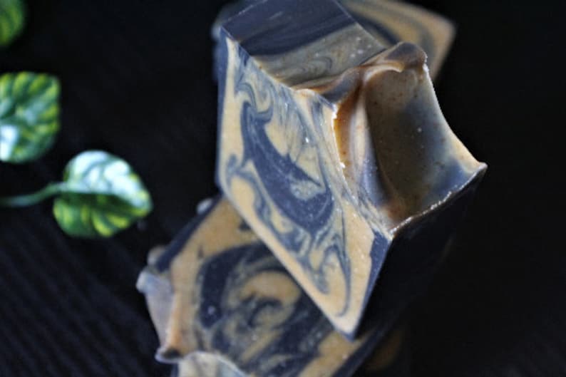 May include: Three bars of handmade soap with a swirl pattern of black and beige. The soap is stacked on top of each other.
