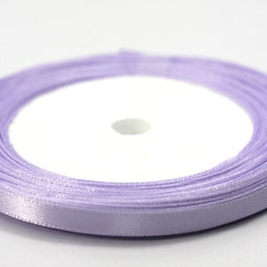 May include: A spool of lavender satin ribbon. The ribbon is wound around a white cardboard spool.