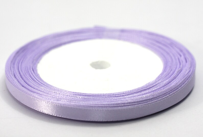 May include: A spool of lavender satin ribbon. The ribbon is wound around a white cardboard spool.
