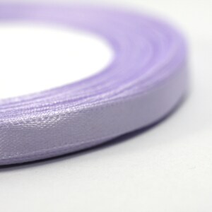May include: A roll of lavender satin ribbon. The ribbon is wound tightly and the edges are visible.