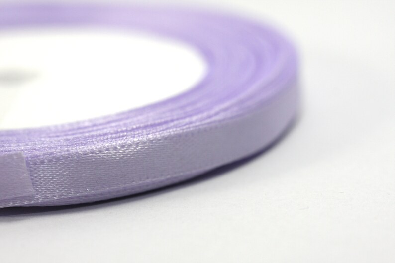 May include: A roll of lavender satin ribbon. The ribbon is wound tightly and the edges are visible.