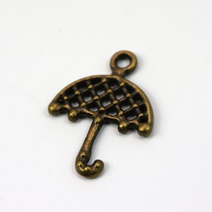 May include: A bronze-colored metal charm in the shape of an umbrella. The umbrella has a lattice design and a curved handle.