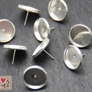 May include: Eight silver-toned earring settings with round bezels and posts. The bezels are smooth and shiny.