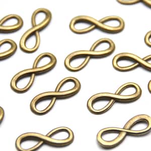 Peut inclure: Un ensemble de breloques en forme de symbole infini de couleur or. Les breloques sont en métal et ont une finition lisse et polie.