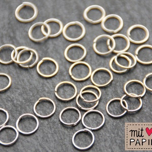Puede incluir: Una colección de anillos de salto de plata y oro, un tipo de anillo de metal utilizado en la fabricación de joyas.