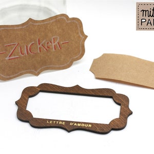 May include: Three brown paper labels with scalloped edges. The top label has the word "Zucker" written in red. The middle label is blank. The bottom label has the words "Lettre D'Amour" written in gold.