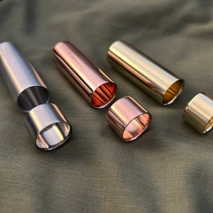 May include: Three metal tubes, one silver, one copper, and one gold, are shown separated into two pieces. The tubes are all the same size and shape.