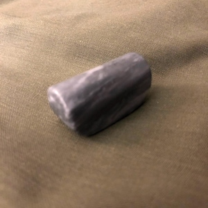 May include: A dark gray, smooth, rounded stone with a marbled pattern.