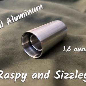 May include: A silver aluminum tube with a smooth finish. The tube is 1.6 ounces and has the text "Full Aluminum" and "Raspy and Sizzley" written on it.