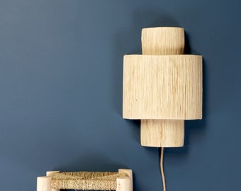 May include: A wooden wall sconce with a layered design. The sconce is made of natural wood and has a warm, rustic look. It is mounted on a blue wall.