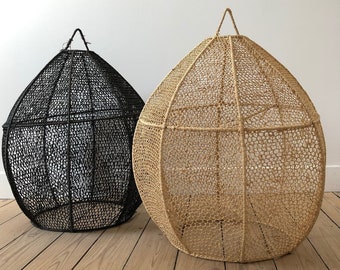 May include: Two woven, teardrop-shaped decorative baskets. One is black, the other is a natural tan colour. Each has a loop at the top for hanging. The baskets are made of a woven material and have an open, airy design.