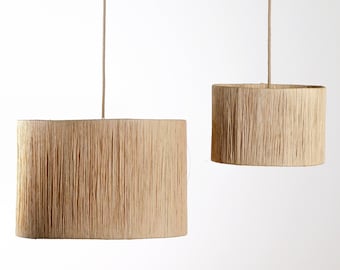 May include: Two natural fiber pendant lights with a woven texture. The larger light is oval shaped and the smaller light is round.