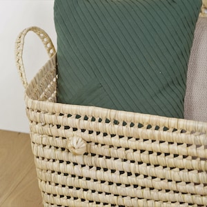 Peut inclure: Un panier en jonc de mer tress&eacute; avec deux poign&eacute;es, rempli d'un coussin &agrave; rayures vertes. Le panier est brun clair et a une texture tiss&eacute;e naturelle.