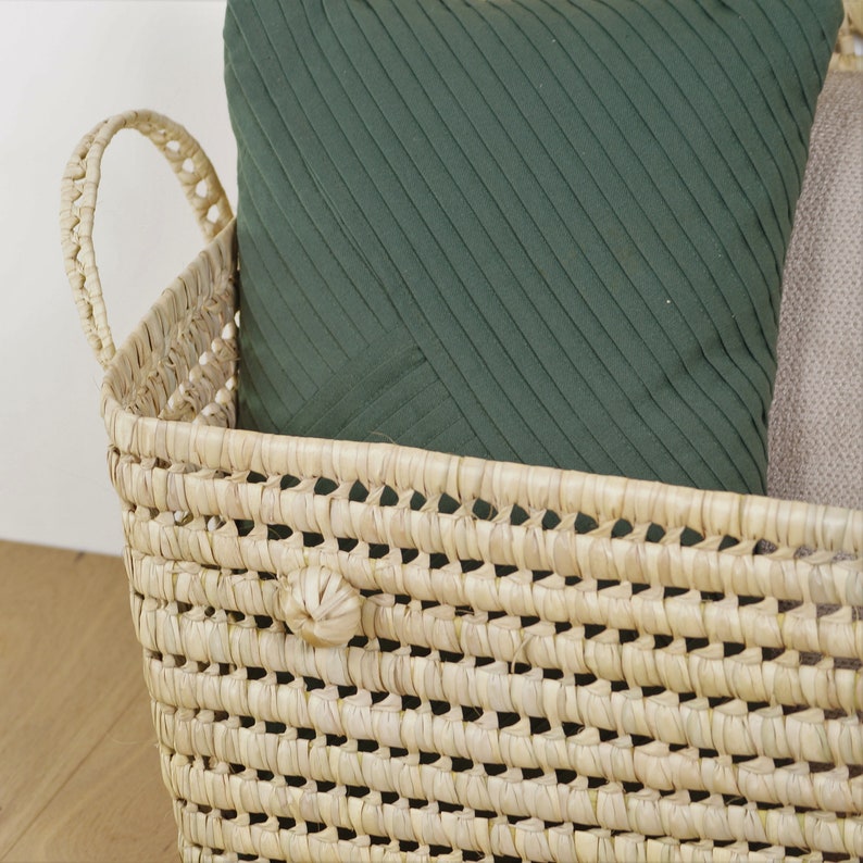 Peut inclure: Un panier en jonc de mer tress&eacute; avec deux poign&eacute;es, rempli d'un coussin &agrave; rayures vertes. Le panier est brun clair et a une texture tiss&eacute;e naturelle.