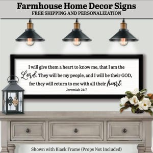May include: Farmhouse style home decor sign with a black frame. The sign displays a Bible verse from Jeremiah 24:7 in a white background. The text is in black script and block letters. The image includes a decorative lantern and flowers.