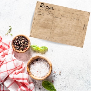 Puede incluir: Una tarjeta de receta vintage con l&iacute;neas para ingredientes, tiempo de preparaci&oacute;n, instrucciones, tiempo de cocci&oacute;n y tiempo de horno. La tarjeta est&aacute; sobre una superficie blanca con un pa&ntilde;o a cuadros rojo y blanco, un peque&ntilde;o taz&oacute;n de sal, un peque&ntilde;o taz&oacute;n de granos de pimienta y hojas de albahaca frescas.