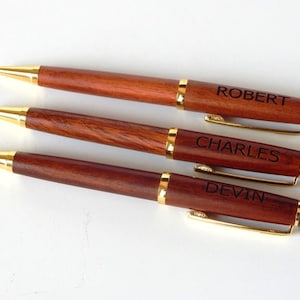 May include: Three wooden pens with gold accents and personalized names: Robert, Charles, and Devin.