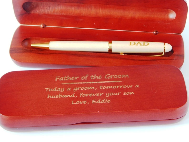 May include: A wooden box with a gold pen inside. The pen has the word "DAD" engraved on it. The box has an engraved message that reads "Father of the Groom Today a groom, tomorrow a husband, forever your son Love, Eddie".