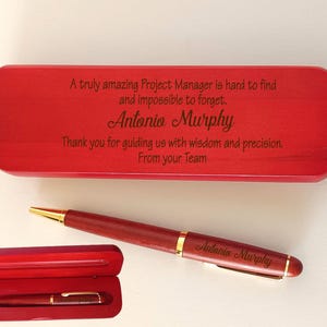 May include: A red wooden pen case with the engraved text: A truly amazing Project Manager is hard to find and impossible to forget, Antonio Murphy. Thank you for guiding us with wisdom and precision. From your Team. A matching red pen with gold trim.