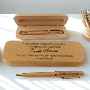 Può includere: Un astuccio in legno di colore chiaro con una penna in legno abbinata, entrambi incisi con il nome Lynette Atkinson. Il coperchio dell'astuccio riporta il testo: A truly amazing Accountant is like a Pearl, rare, precious and hard to find. Lynette Atkinson.