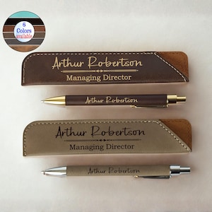 Könnte beinhalten: Zwei personalisierte Stiftsets mit passenden Etuis. Das obere Set ist braun mit goldenem Text, das untere Set ist beige mit schwarzem Text. Jedes Etui und jeder Stift ist mit "Arthur Robertson, Managing Director" graviert.