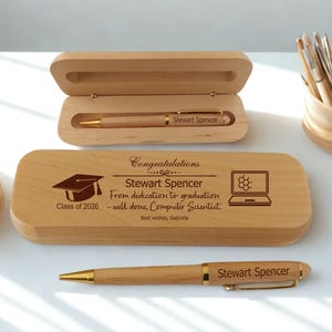 May include: A wooden pen set with a pen and a pen case. The pen case is engraved with a graduation cap, a laptop with a molecular structure, and the text "Congratulations Stewart Spencer". The pen is engraved with "Stewart Spencer".