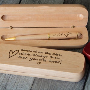 May include: A wooden pen box with a pen inside. The box is engraved with the words "Constant as the Stars above, always know that you are loved!" and a heart. The pen is engraved with the words "I love you".