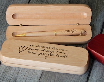May include: A light-colored wooden pen with gold accents and the engraved text I love you, resting inside an open matching wooden case. The lid of the case features an engraved heart and the text Constant as the stars above, always know that you are loved! J.