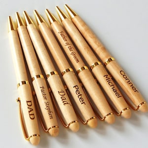 May include: Seven wooden pens with gold accents and personalized engravings. The engravings include "Dad", "Pastor Stephen", "DAD", "Peter", "Father of the Groom", "Michael", and "Conner".