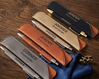 May include: Four personalized pens with matching sleeves in black, tan, brown, and gray. Each pen and sleeve is engraved with a name and the word Groomsman. The black pen has gold accents, while the others have silver accents. Two cufflinks are included.