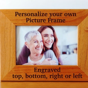 May include: A wooden picture frame with a light brown finish. The frame has a photo of two women smiling. The text "Personalize your own Picture Frame" is engraved on the top of the frame. The text "Engraved top, bottom, right or left" is engraved on the bottom of the frame.