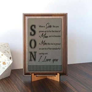 May include: A wooden plaque with a gray background and black lettering. The plaque reads "When a Son like you grows up to be the kind of Man you've become A Mom like me is proud as can be of her wonderful caring son. I Love you".