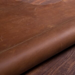 May include: A close-up of a rolled piece of brown leather. The leather has a natural, rustic look and feel.