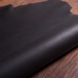 May include: A close-up of a black leather sheet rolled up on a wooden surface.