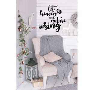 May include: A white armchair with a gray knitted throw blanket and a white pillow. The wall behind the chair has a black vinyl decal that reads "Let heaven and nature sing".