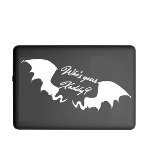 May include: A black rectangular case with a white bat-wing design and the text "Who's your Kaddy?" in a stylized font. The design features two bat wings and a playful, spooky theme.