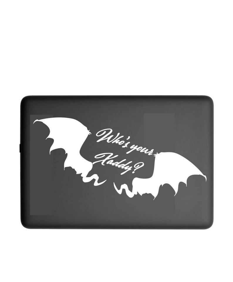 May include: A black rectangular case with a white bat-wing design and the text "Who's your Kaddy?" in a stylized font. The design features two bat wings and a playful, spooky theme.